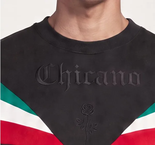 Chest close-up after: lettering reads Chicano with the embroidered rose